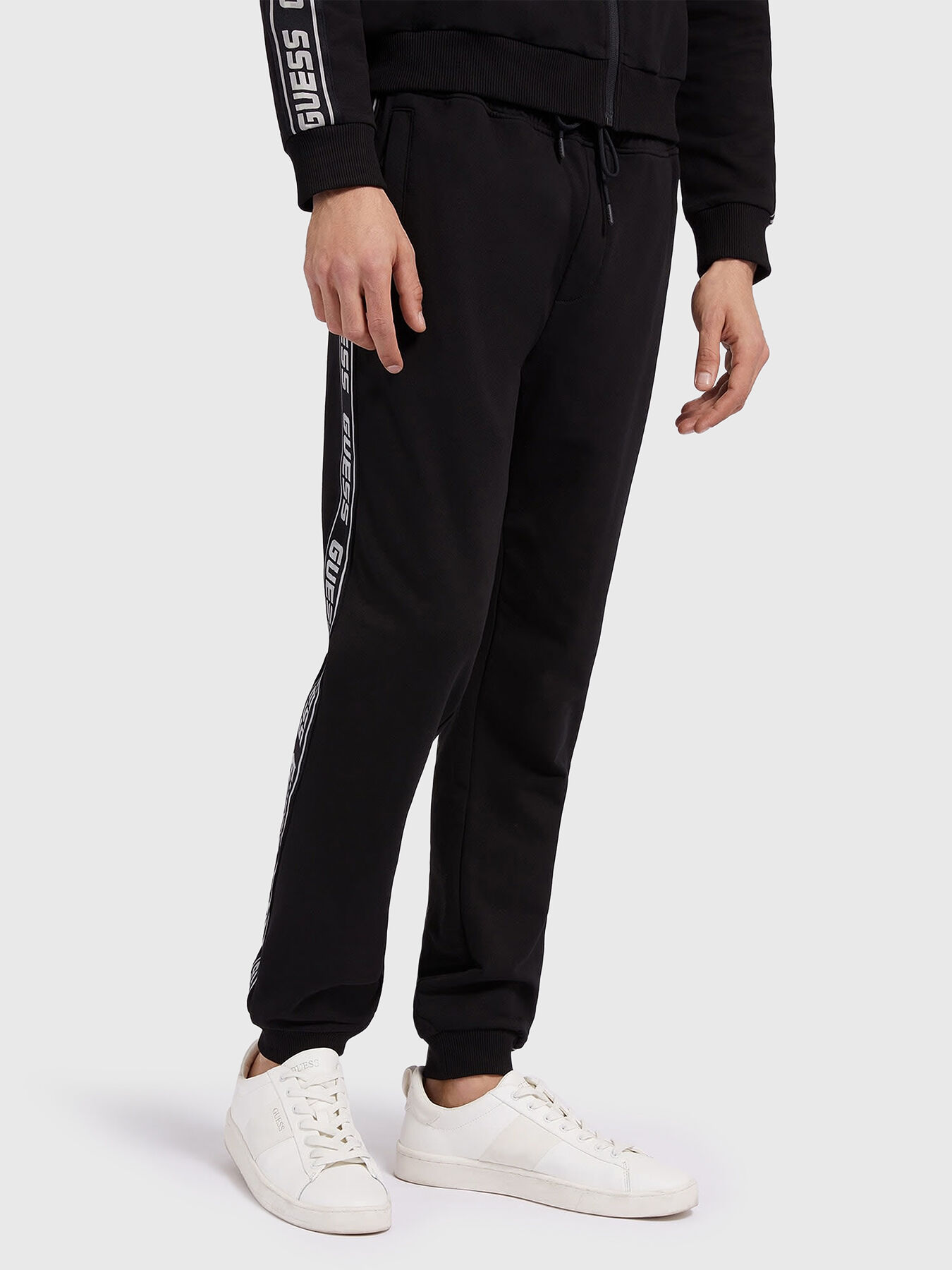 Black sports pants with logo edging brand GUESS — Globalbrandsstore.com/en